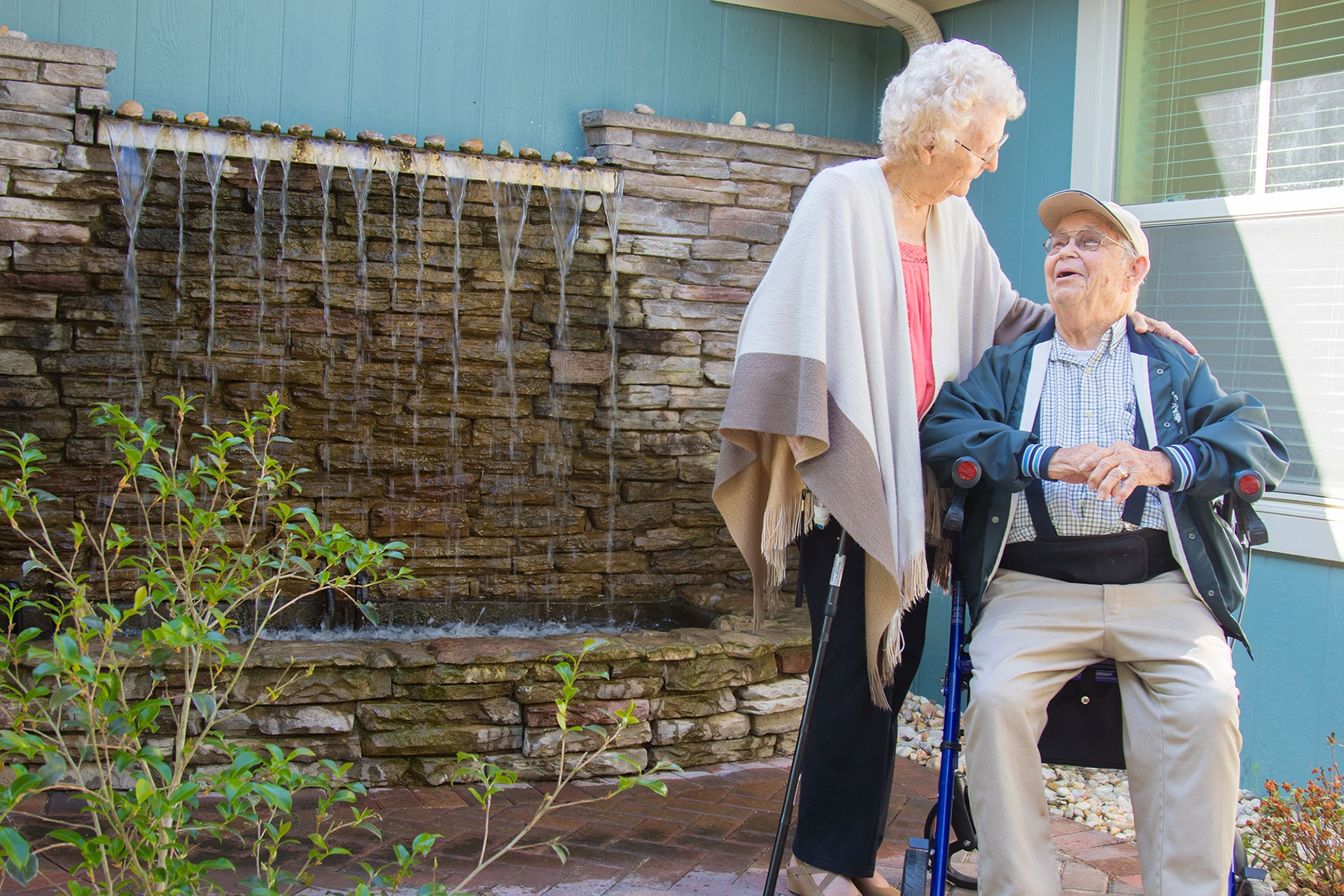 Elderly couple enjoying a moment near a water feature.
